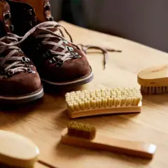 Brązowe buty zamszowe i szczotki do czyszczenia. Dowiedz się, jak usunąć wosk z butów zamszowych, by znów wyglądały jak nowe.