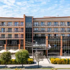 Elegancki hotel Leda Spa z restauracją La Maison, z licznymi balkonami i przeszklonym wejściem, otoczony zielenią.