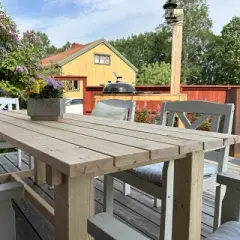 Bygga utebord: en trästomme på gräsmattan, ett färdigt bord med stolar på en altan, och en person som mäter trä för bygget.