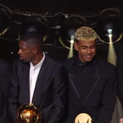 Piłkarze na gali Złotej Piłki, jeden z nich trzyma trofeum.