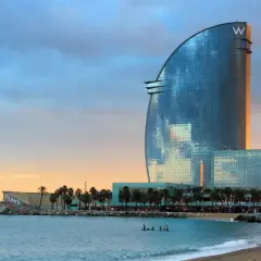 La spiaggia di notte a Barcellona, con il moderno Hotel W che riflette il cielo al tramonto.