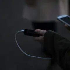Ręka trzyma powerbank i smartfon, podłączone kablem. Elektronika w samolocie to klucz do rozrywki podczas podróży.