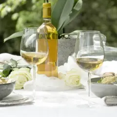 Bordeaux blanc moelleux, deux coupes de vin, deux bols de risotto et des roses blanches sur une table dressée en extérieur.