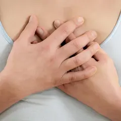 Hände umfassen die Brust, als ob sie brustbein schmerzen lindern wollen.