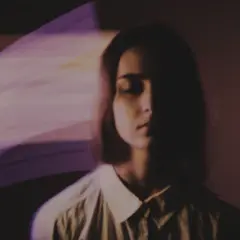 Kobieta z zamkniętymi oczami, otoczona fioletowymi, rozmazanymi światłami, jak po zażyciu lsd.