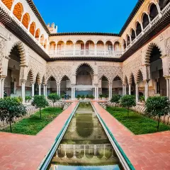 Wspaniały dziedziniec Alcazar z basenem, zielenią i misternymi łukami.