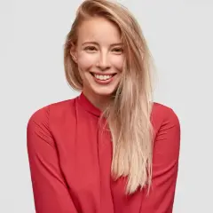 Uśmiechnięta blondynka w czerwonej bluzce. Czy toner się wyplukuje? Jej włosy są jasne i lekko potargane.