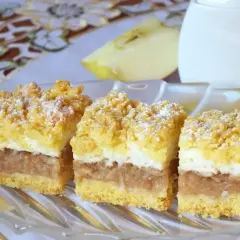 Pyszna szarlotka z bezą i kruszonką, z jabłkami i cukrem pudrem, na talerzu.
