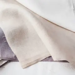 Trois tissus en lin, l'un violet, l'autre beige et le dernier blanc, prêts à blanchir le linge pour un éclat parfait.