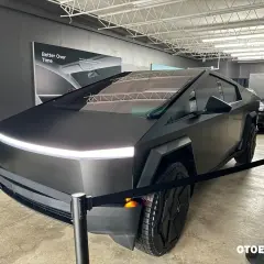 Futurystyczny Cybertruck w matowej czerni, z charakterystycznym pasem LED z przodu, prezentowany na wystawie.