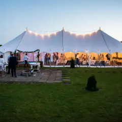 Elegancki wynajem namiotu na wesele. Goście bawią się w oświetlonym namiocie, a na zewnątrz panuje wieczorny spokój.