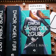 Książki z serii "Dwór cierni i róż" Sarah J. Maas. Tom 6 "Dwór skrzydeł i zguby" z piękną okładką.