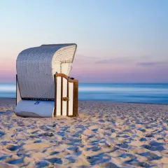 Pusta plaża o zachodzie słońca, idealna na tanie miejscowości nad morzem. Wygodny kosz plażowy czeka na turystów.