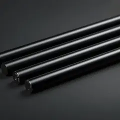 Quattro barre cilindriche con finitura opaca, risultato di un'accurata anodizzazione nera, disposte diagonalmente su sfondo scuro.