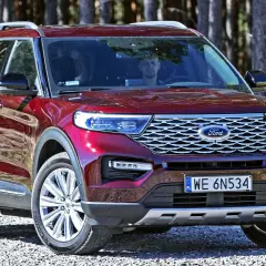 Czerwony Ford Explorer, jeden z wielu modeli tej marki, zaparkowany na leśnej drodze.