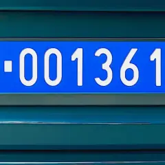 Niebieskie tablice dyplomatyczne z białym napisem W-001361 na ciemnozielonym tle pojazdu.