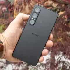 Czarny smartfon marki Sony z potrójnym aparatem, trzymany w dłoni na tle jesiennych liści.