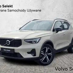 Jasny beżowy Volvo XC40, używane z salonu, prezentuje się elegancko na tle betonowej ściany.