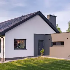 Nowoczesny dom z białymi i grafitowymi ścianami, prezentujący najmodniejsze kolory elewacji. Dachówka w ciemnym kolorze.