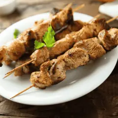 Grillade kycklingspett, tavuk sis, på en vit tallrik med persilja.