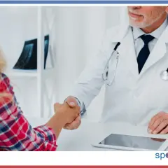 Lekarz specjalista w białym kitlu wita pacjentkę uściskiem dłoni. Rozpoczyna się zmiana lekarza specjalisty w trakcie leczenia.