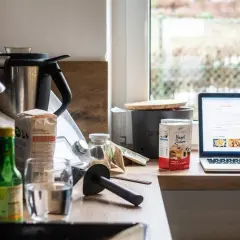 Na blacie kuchennej stoi Thermomix, obok składniki i laptop z przepisem. Właśnie szukasz informacji, jak zapłacić abonament w Thermomixie.