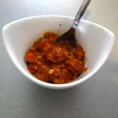 Czerwona pasta curry w białej miseczce z łyżką.