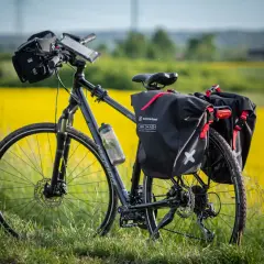 Rower z sakwami Extrawheel gotowy na wyprawę. Jakie sakwy rowerowe wybrać na długą trasę? Te czarne, wodoodporne, z czerwonymi akcentami, wyglądają na solidne.