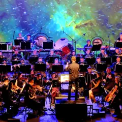 Orkiestra symfoniczna wykonuje najlepszą muzykę filmową wszech czasów na tle kosmicznej projekcji.