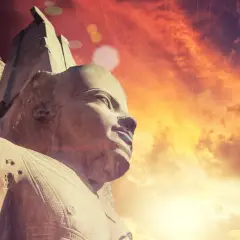Kamienna głowa faraona na tle zachodzącego słońca. Skarabeusz co symbolizuje? Odrodzenie i ochronę.