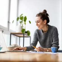Uśmiechnięta kobieta pracuje przy laptopie, planując swoje **2 dni wolne za pracę w niedzielę**.