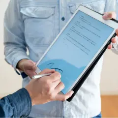 Firma electrónica en tablet, un hombre firma un documento digital con un stylus. El acto tiene pleno p.p. significado jurídico.