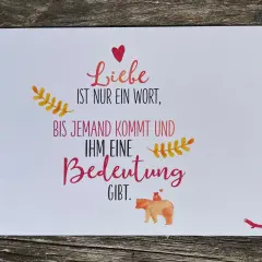 Eine Karte mit der Aufschrift "Liebe ist nur ein Wort, bis jemand kommt und ihm eine Bedeutung gibt." Ein Bärenbaby sitzt auf dem Rücken eines Bären.