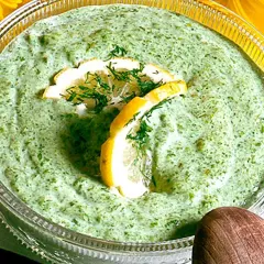 En skål med krämig salsa verde, garnerad med citronskivor och dill. Perfekt till sommarmaten!