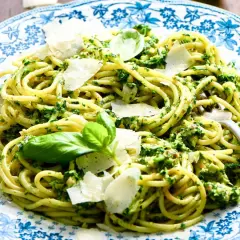 Pâtes au pesto, une recette italienne savoureuse avec des copeaux de parmesan et des feuilles de basilic frais.