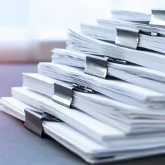 Stos dokumentów z klamrami. Zastanawiasz się, jakie dokumenty są potrzebne do sprzedaży działki rolnej? Oto stos papierów, które mogą być kluczowe.