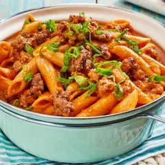 Herzhaftes One Pot Pasta mit Hackfleisch und einer cremigen Tomatensoße, garniert mit Frühlingszwiebeln.