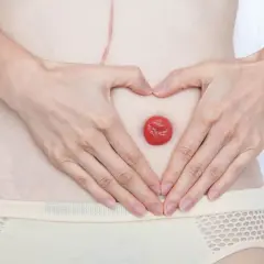 Dłonie tworzą serce wokół stomii, symbolizując akceptację dla wydalania kału odbytem po stomii.