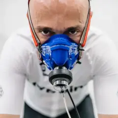Intensywny trening, badanie **pułapu tlenowego**. Mężczyzna w masce analizującej oddech, skupiony na wysiłku.