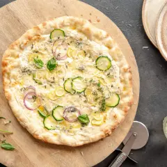 Pyszna pizza bianca z cukinią, cebulą i cytryną, ozdobiona bazylią i tymiankiem.