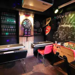 Ambiance de baby bar avec fléchettes, baby-foot et murs décorés de vinyles rock.