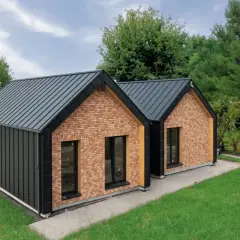 Nowoczesny dom drewniany z ceglanymi akcentami i grafitowym dachem, otoczony zielenią.