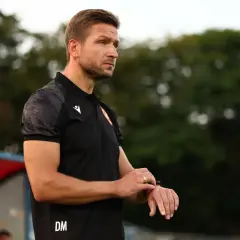 Trener Piasta Gliwice, Dariusz Marzec, spogląda na zegarek, analizując przebieg meczu.