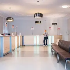Recepcja w nowoczesnej klinice medycznej z poczekalnią i klientem przy ladzie.