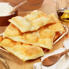 Piatto di gnocco fritto di Ferrara, dorato e soffice, con farina, olio e spighe di grano.