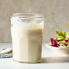 A jar of creamy miso dressing sits next to a fresh salad, ready to add a savory umami kick.