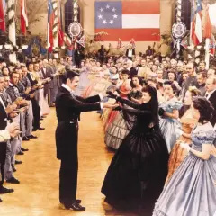 Scarlett O'Hara i Rhett Butler tańczą na balu. W tle widać całą obsadę filmu "Przeminęło z wiatrem" w historycznych strojach.