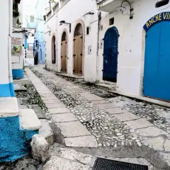 Urokliwa uliczka w Bari, z brukowanym chodnikiem i niebieskimi drzwiami. Idealne miejsce, by odkryć, co zobaczyć w okolicy.