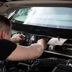 Mechanik sprawdza wiązkę w samochodzie, podłączając złącze elektryczne w komorze silnika.