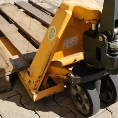 Ein Hubwagen hebt eine Holzpalette an. Dies ist ein gängiges Werkzeug im Lager, um Waren zu bewegen.